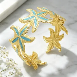 Detailansicht der blauen Emaille-Seesterne und des goldenen Hohlmusters auf dem Armreif.