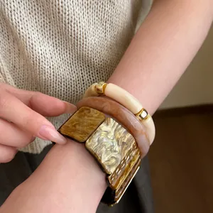 Primer plano detallado de pulseras geométricas de resina y brazaletes de ámbar en la muñeca