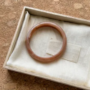 Vista detallada de un elegante brazalete de resina veteada ámbar en una caja de regalo.