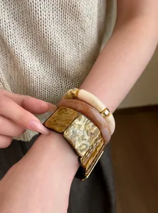 Detalle de tres pulseras apilables de resina con patrón de mármol ámbar y dorado