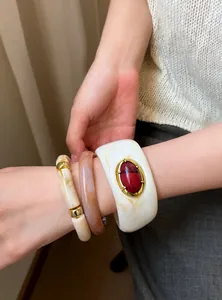 Vista detallada de pulseras de resina apiladas en blanco mármol y ámbar con joya