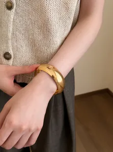 Primer plano detallado de un brazalete geométrico de resina dorada elegante para mujer