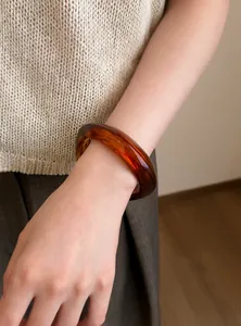 Brazalete redondo geométrico de resina ámbar en la muñeca con un estilo sencillo