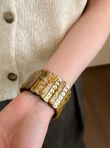 Primer plano de un brazalete geométrico de resina ámbar y metal dorado estilo vintage