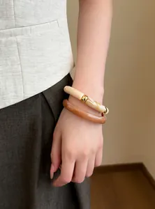 Detalle de brazaletes geométricos de resina en capas en tonos beige mármol y ámbar