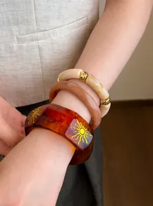 Primer plano de pulseras de resina geométricas apilables en tonos ámbar y crema.