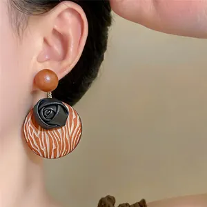Detailed view of Bohemian wooden earrings with a black rose and textured disk for a retro look.