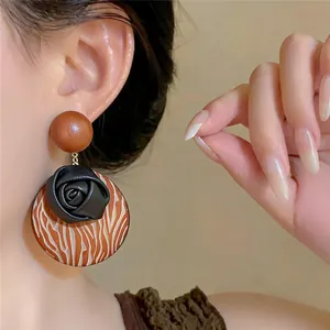 High detail close-up of a bohemian wooden flower earring worn by a model in soft light