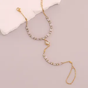 Detalle de cadena de mano en acero dorado con circonitas blancas y piedra gota