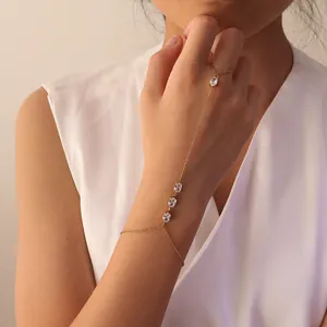 Elegante pulsera de mano en acero dorado con circonitas ovales brillantes en mano mujer