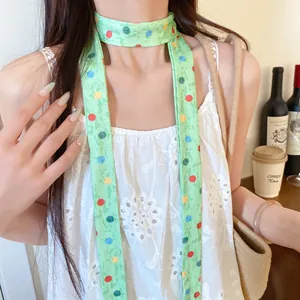 Detailweergave van een lichtgroene gestippelde smalle sjaal gedragen als modeketting.