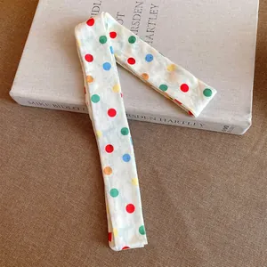 Detailweergave van de kleurrijke stippen polyester lint sjaal ketting op een boek