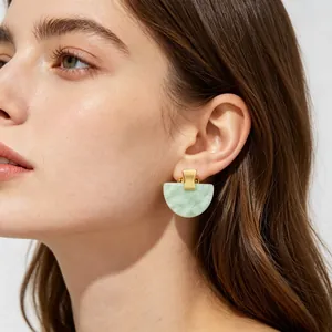 Gros plan d'un mannequin portant des boucles d'oreilles en résine vert menthe et or
