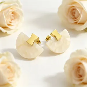 Vue macro de boucles d'oreilles géométriques en résine en éventail avec dorure.