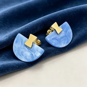 Gros plan sur des boucles d'oreilles en résine bleue marbrée avec détails dorés