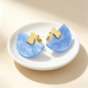 Vue détaillée des boucles d'oreilles en résine bleue marbrée avec accents dorés