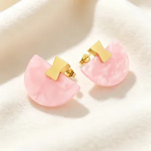 Gros plan de boucles d'oreilles en résine rose éventail avec des détails dorés élégants