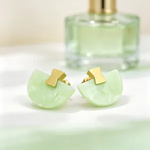 Gros plan de boucles d'oreilles en résine vert macaron avec des accents dorés géométriques