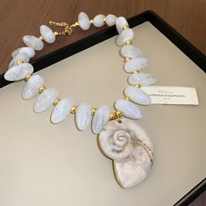 Detail shot of white marble acrylic beads and a large nautilus shell pendant necklace.