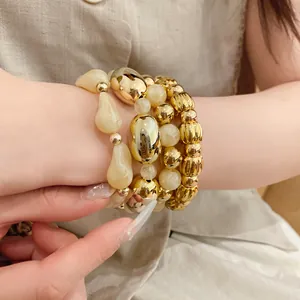 Primer plano de un set de pulseras elásticas de acrílico y perlas doradas en muñeca