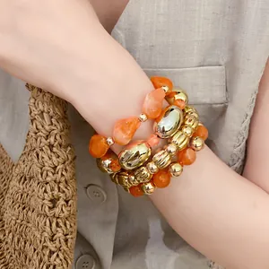 Primer plano de pulseras de cuentas de acrílico naranja y metal dorado.