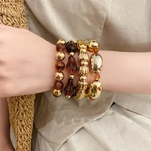 Vista detallada del conjunto de pulseras de acrílico dorado y ámbar geométrico