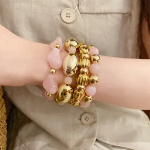 Primer plano de un juego de pulseras elásticas con cuentas geométricas rosas y doradas