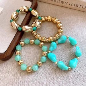 Vista de detalle del conjunto de pulseras elásticas con cuentas acrílicas en oro y verde