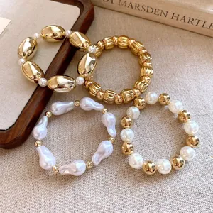 Primer plano de un set de 4 pulseras elásticas con cuentas doradas y de perlas
