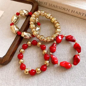 Vista detallada de pulseras elásticas de acrílico rojo y oro con diseños geométricos