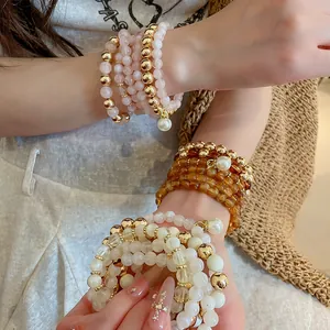 Close-up of stacked acrylic pearl beaded bracelets in gold, pink and amber tones