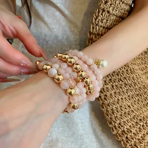 Close-up detail of a luxurious pink and gold beaded bracelet set worn on a model's wrist