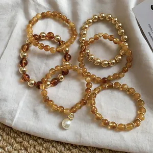 Detailed macro view of amber acrylic and gold beaded bracelet set with pearl charm