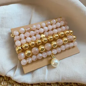 Detail of pink and gold beaded bracelet set with pearl charm on linen background