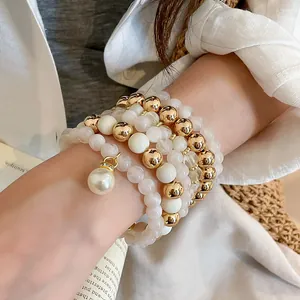 Detailed view of layered acrylic pearl and gold-toned beaded bracelet set on wrist