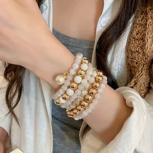 Close-up of elegant multi-layer beaded bracelet set with gold accents and pearls