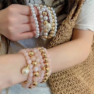 Close-up detail of stacked acrylic pearl and elegant gold-toned beaded bracelet set.