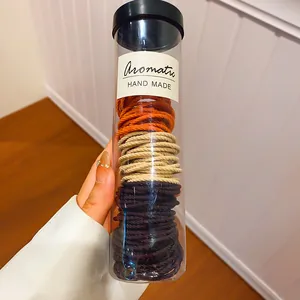 Gedetailleerd overzicht van gekleurde handgemaakte haarelastieken in een plastic koker