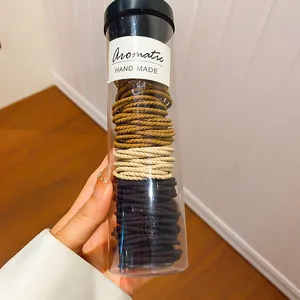 Detailweergave van diverse elastische haarelastiekjes in een doorzichtige cilindrische koker