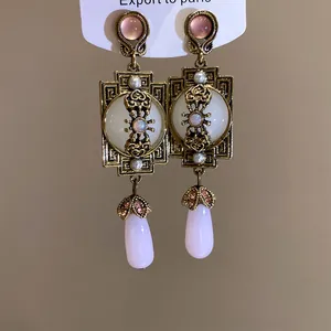 Gros plan sur les boucles d'oreilles pendantes vintage dorées avec résine rose et perles