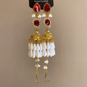 Détail de boucles d'oreilles vintage à pampilles dorées avec perles blanches