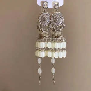 Gros plan de boucles d'oreilles vintage argentées à pompons avec perles blanches et cristaux