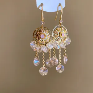 Détail de boucles d'oreilles vintage en or avec cristaux roses et pendentifs en goutte.