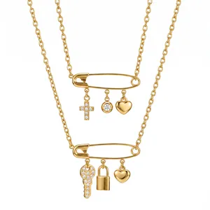 Nahaufnahme von goldenen Sicherheitsnadel-Anhängern mit Schlüssel- und Herzcharme.