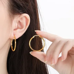Elegant gold stainless steel large hoop earrings displayed on model ear and held in hand