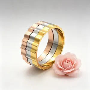 Close-up of three 3mm serrated stainless steel rings in gold, silver, and rose gold
