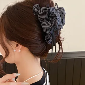 Detail of a Korean striped fabric bow hair claw clip with elegant tassel ribbons