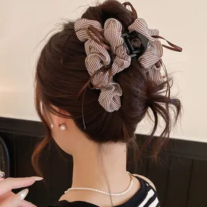 Macro view of an elegant striped fabric bow hair claw clip styled in a classic updo hairstyle.
