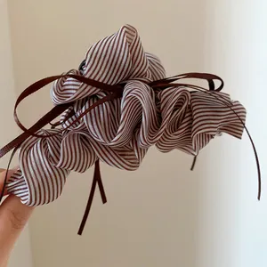 Detailed macro view of a striped pleated hair claw clip featuring brown ribbon tassels