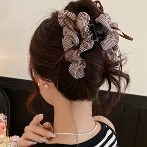 Detail shot of a brown striped fabric bow hair claw clip styled in a modern updo